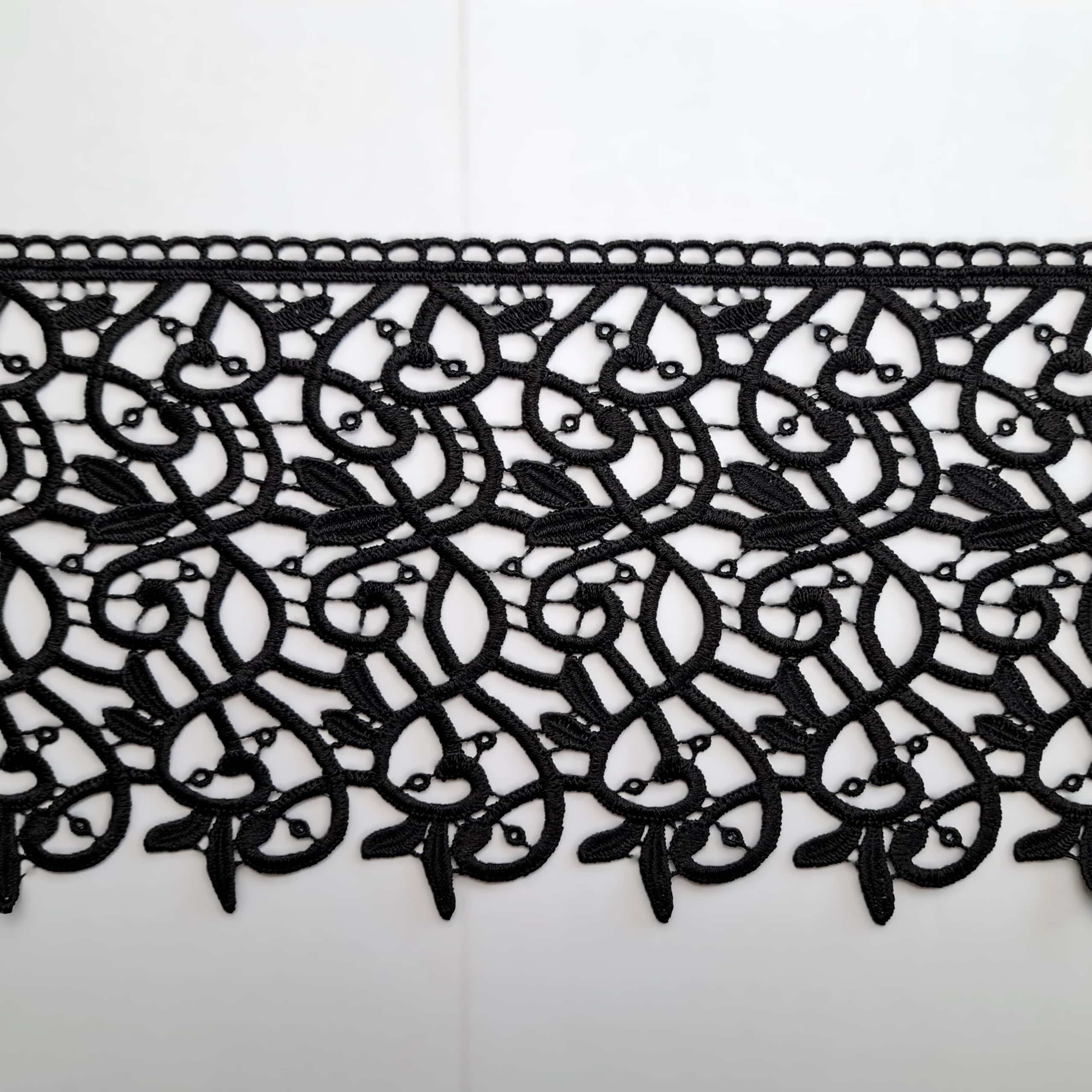 Czarna koronka z bogatym wzorem na białym tle, idealna do eleganckich projektów krawieckich.