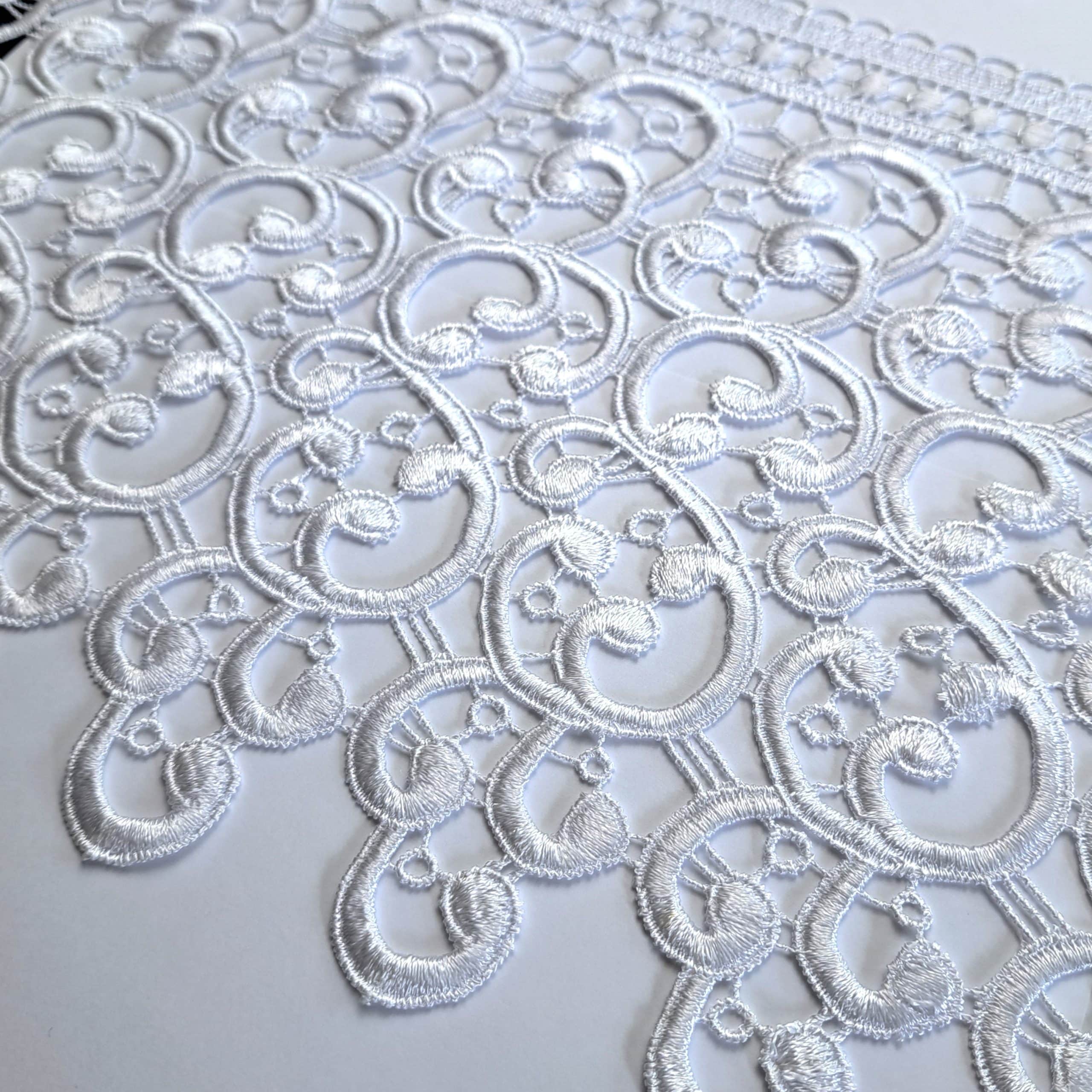2521-20 1 Elegancka biała koronka z motywem roślinnym, idealna do dekoracji wnętrz i projektów odzieżowych.