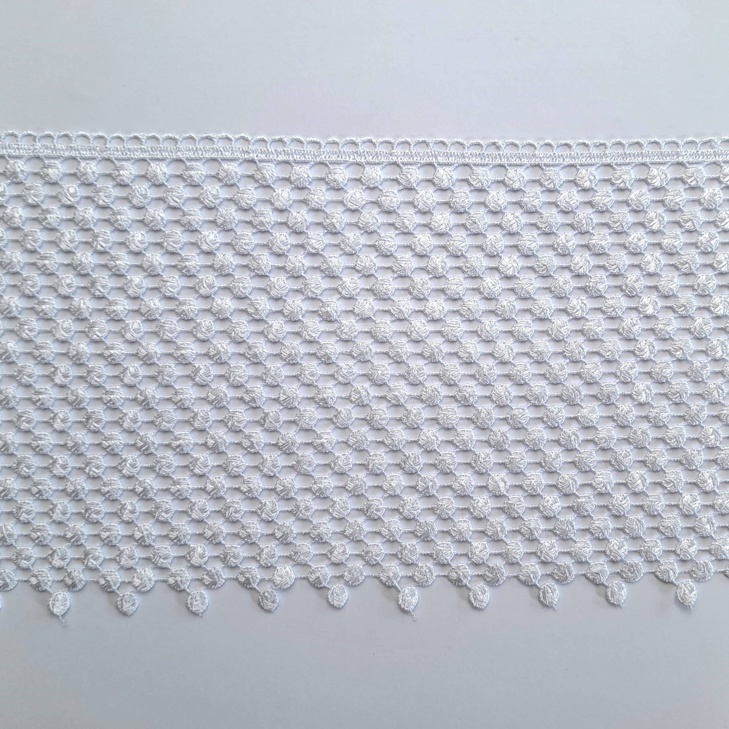3236-20 3 Biała koronka o delikatnym wzorze na białym tle, idealna do dekoracji i projektów rękodzielniczych.