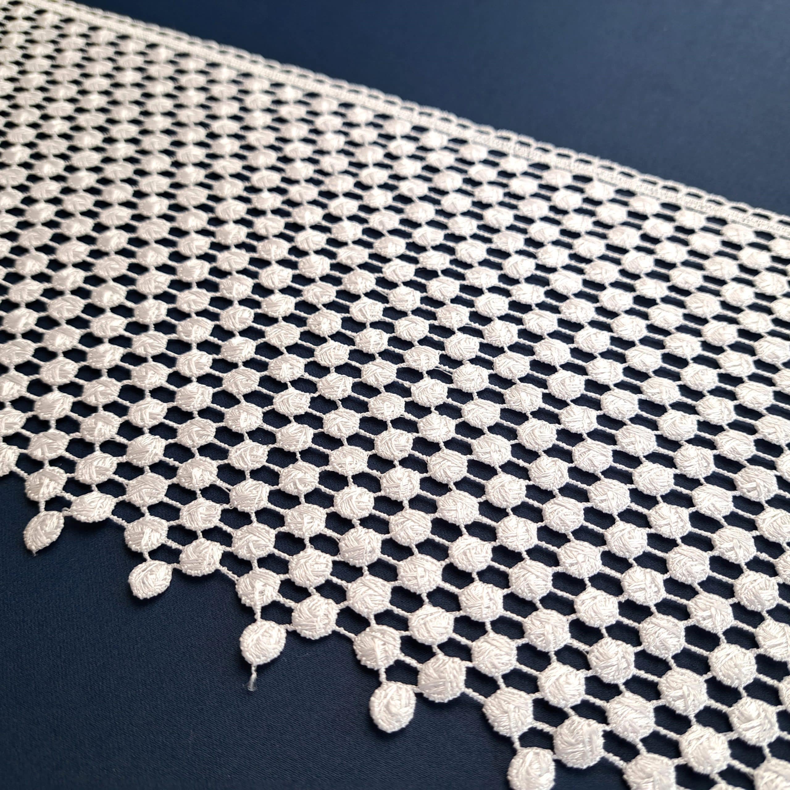 3236-20 4 Biała koronka na granatowym tle z geometrycznym wzorem i delikatnymi krawędziami.