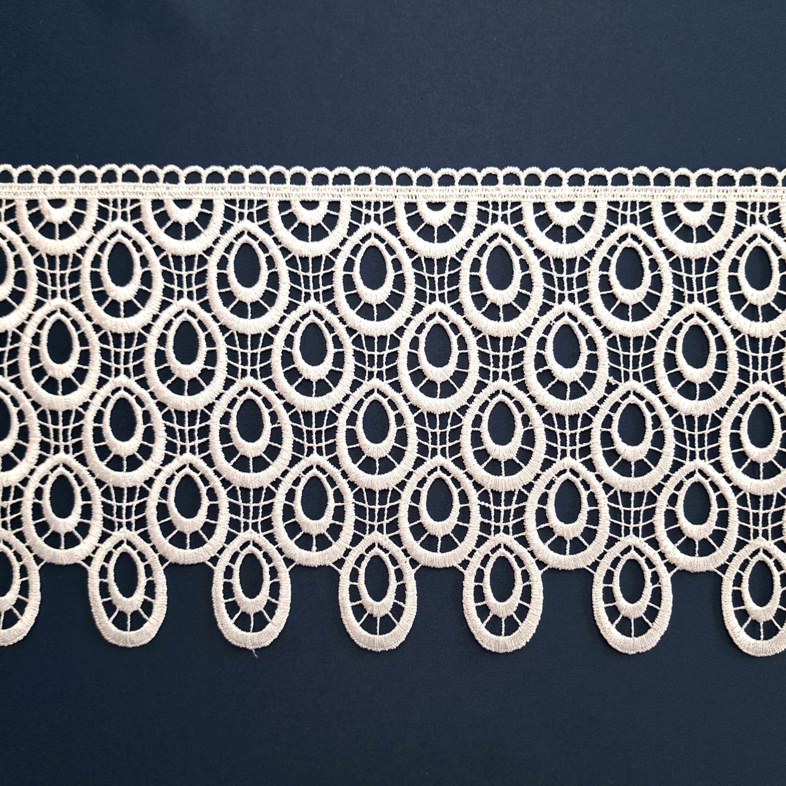Koronkowy wzór w jasnym kolorze na ciemnym tle, elegancka dekoracja tekstylna z symetrycznym wzorem.