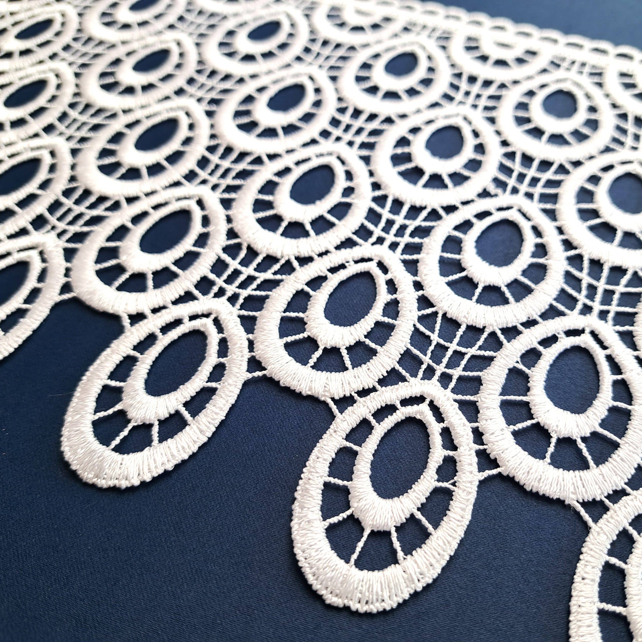 Koronkowa serweta z owalnym wzorem na ciemnoniebieskim tle, elegancka dekoracja stołu.