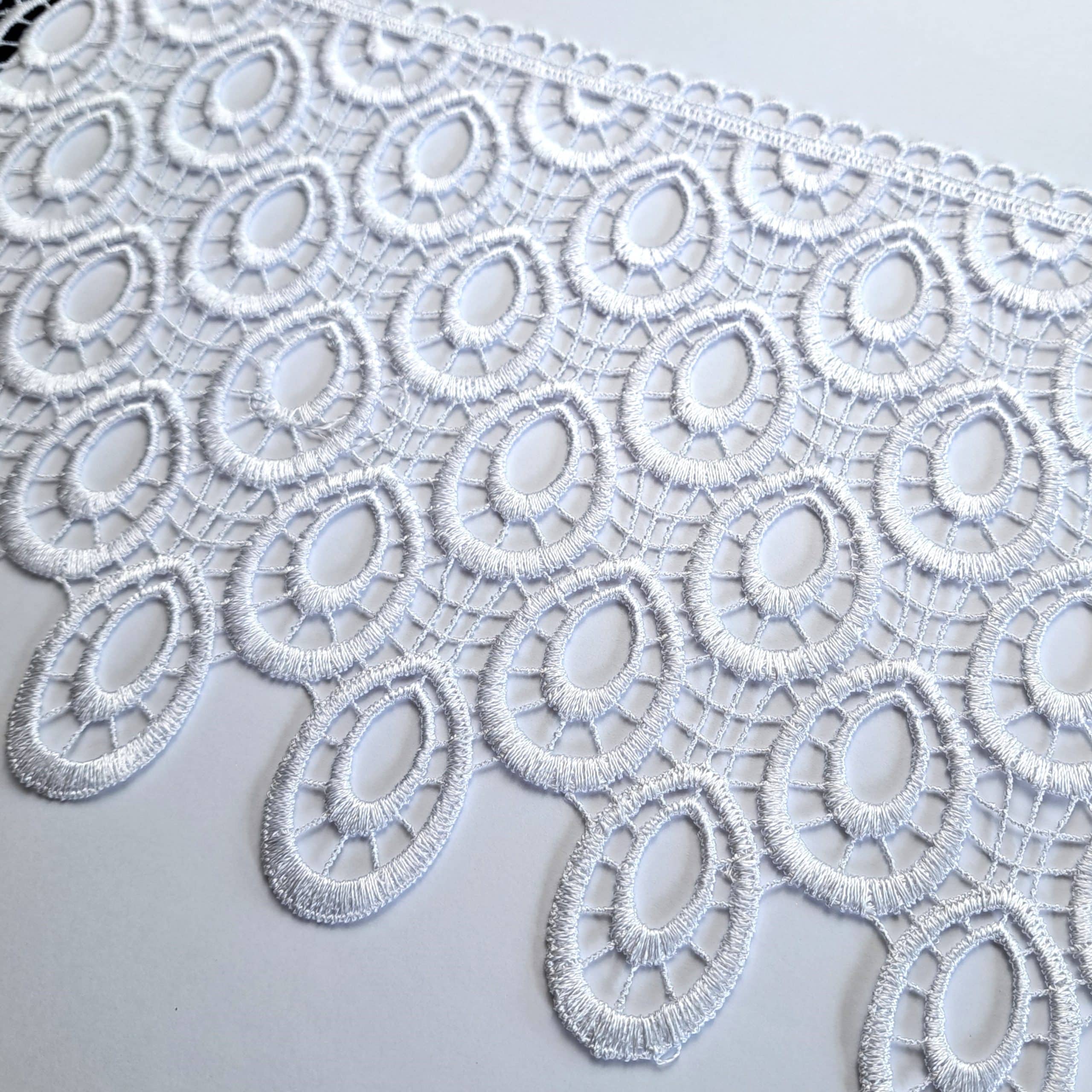 Biała koronka o owalnym wzorze na białym tle, delikatny i elegancki design.