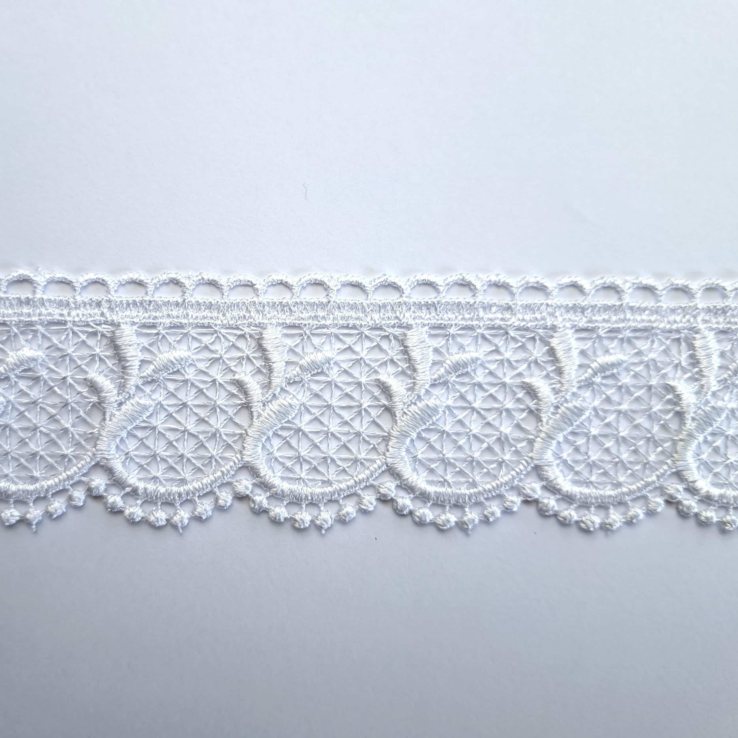 Biała koronka z delikatnym wzorem, idealna do dekoracji odzieży i tkanin, na białym tle.