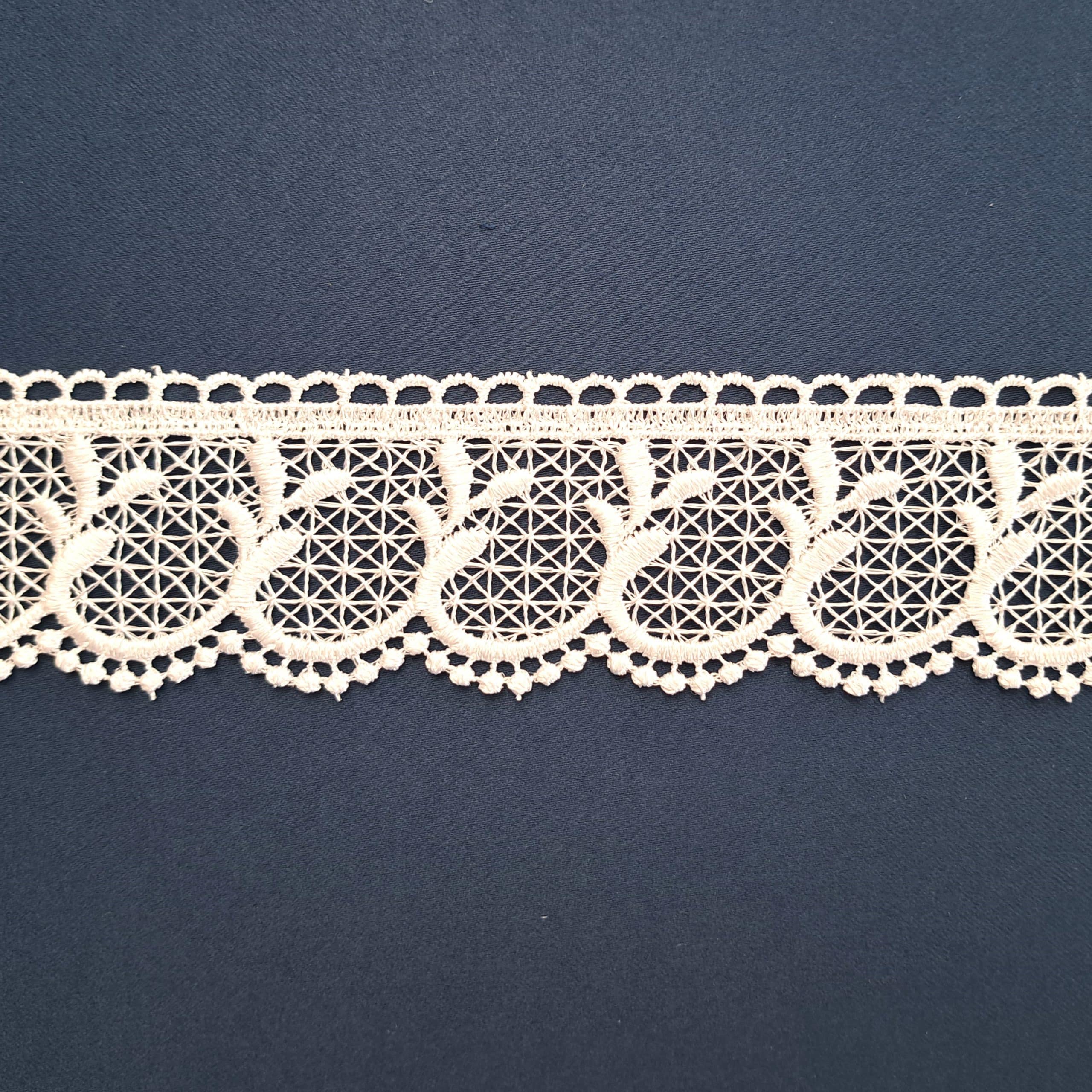 Koronkowa dekoracja na granatowym tle, ozdobiona delikatnym wzorem kwiatowym.