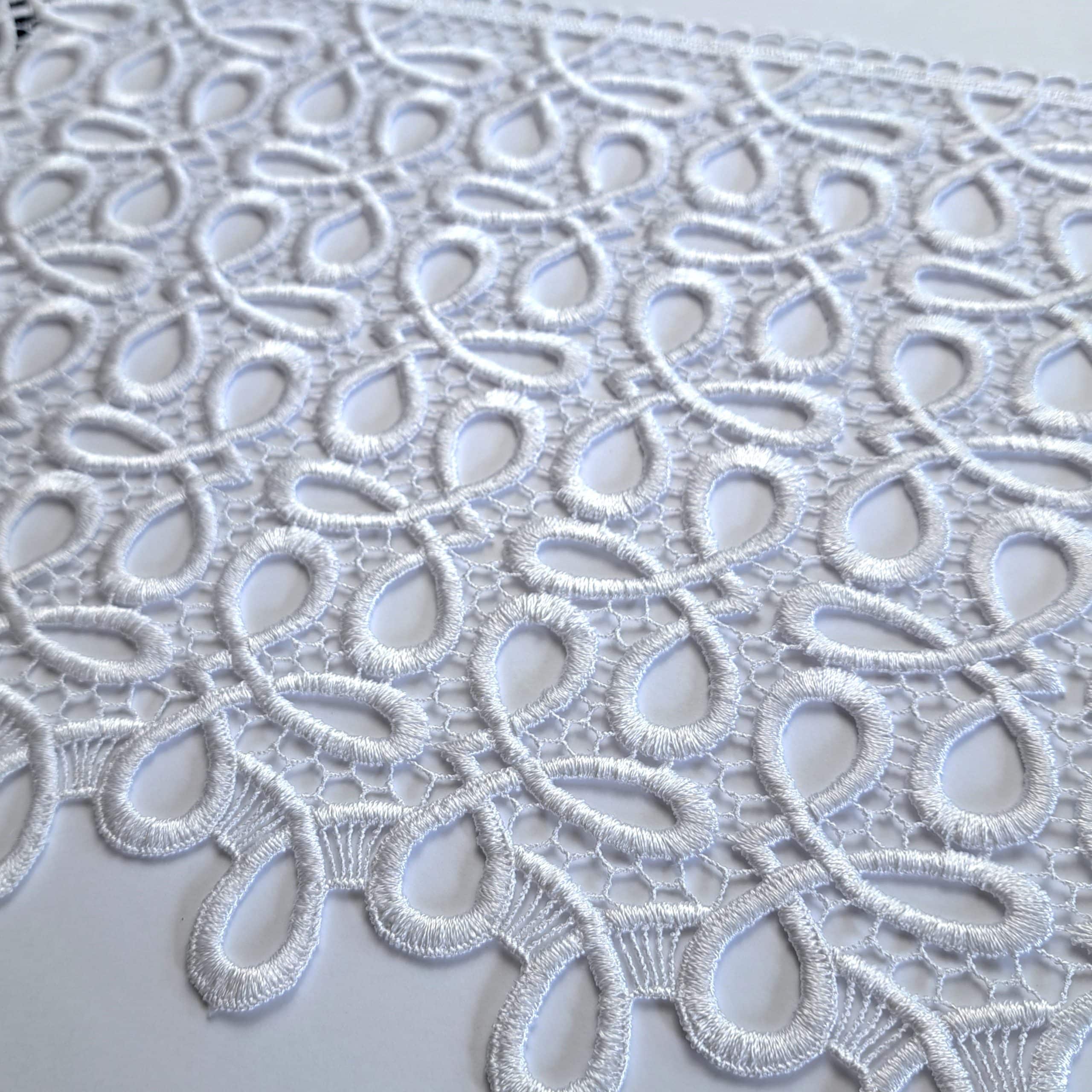 Biała koronka o delikatnym wzorze zbliżenie, elegancki design materiału dekoracyjnego.