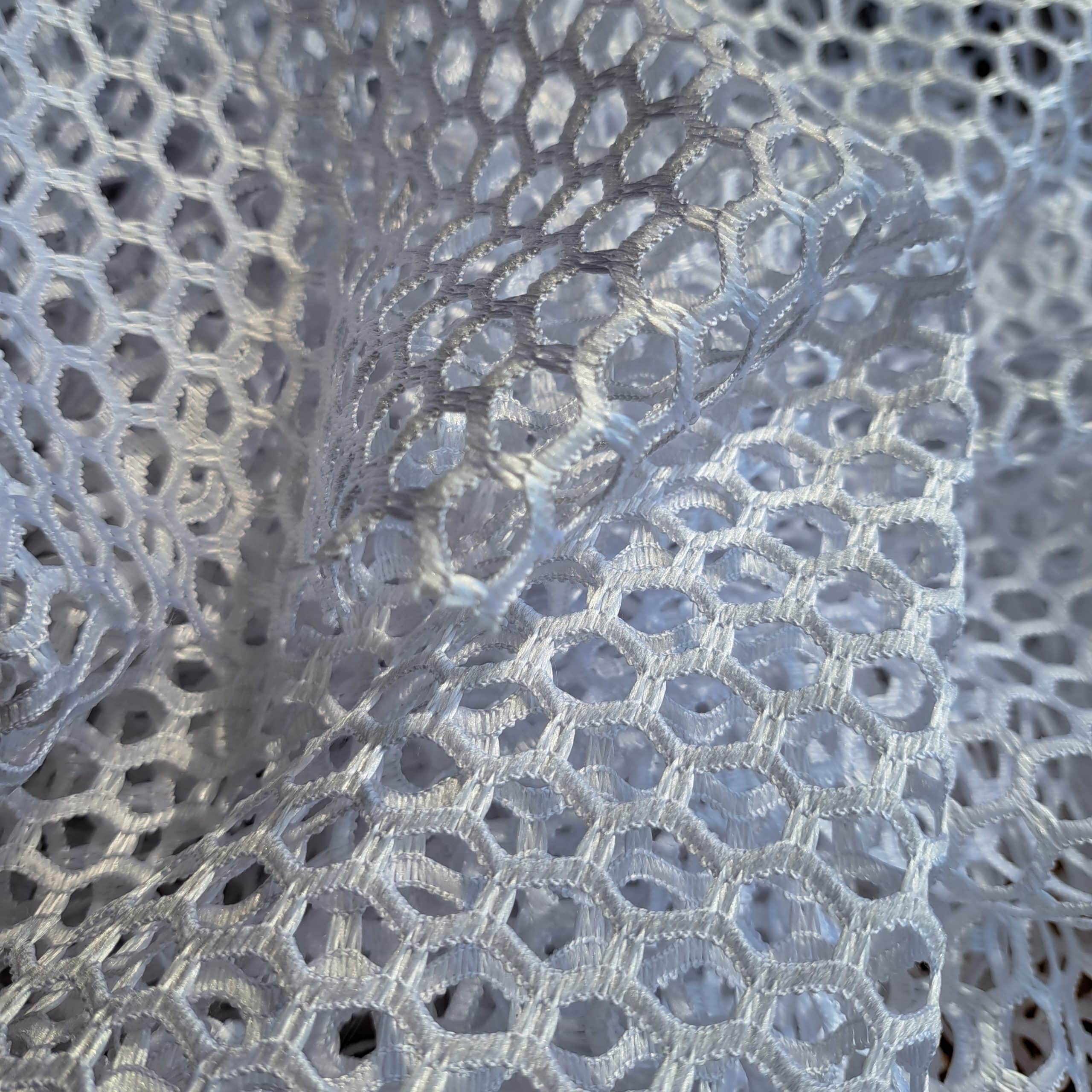 11607 bi 4 Biała koronkowa tkanina z bliska, przedstawiająca szczegółowy wzór sześciokątnych oczek.