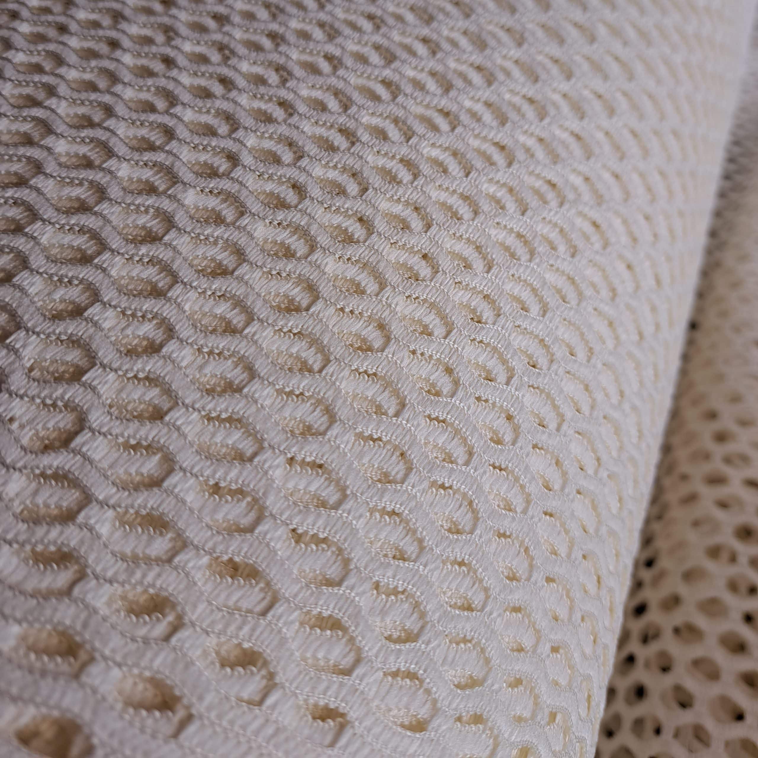 Biały materiał z ażurowym, heksagonalnym wzorem, tekstura tkaniny, zbliżenie, detal dekoracyjny.