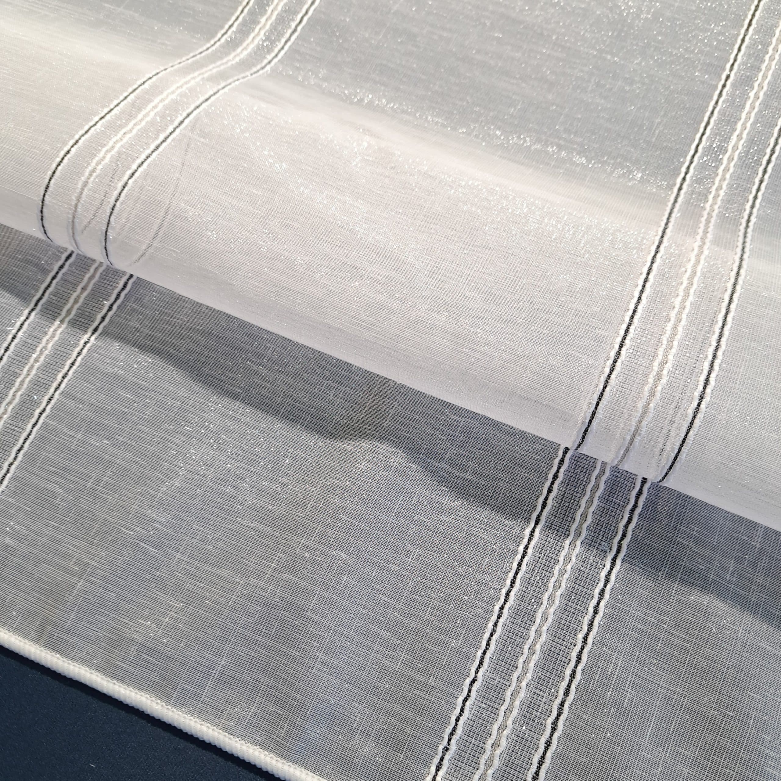 Biała tkanina z delikatnymi pionowymi liniami na ciemnym tle, idealna do eleganckich zasłon lub obrusów.