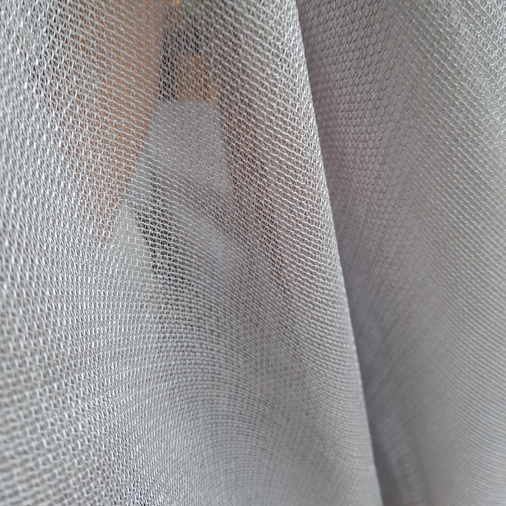 Przezroczysta zasłona z delikatnym wzorem, przepuszczająca światło do wnętrza.