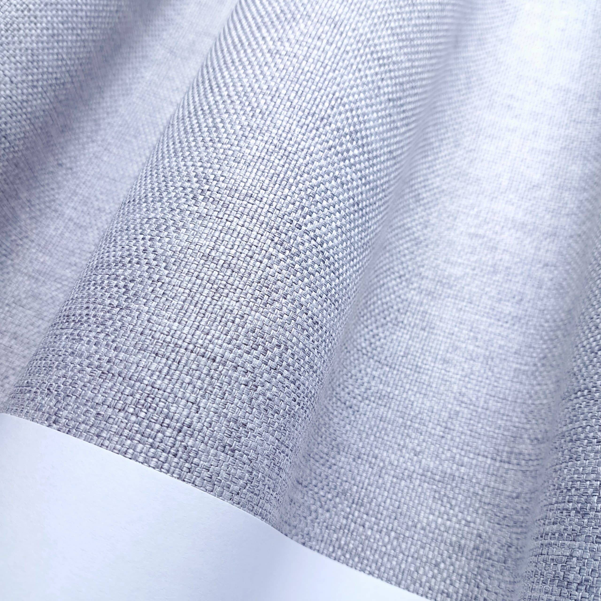 Szara tkanina o fakturze splotu, ułożona w miękkie fale, idealna na zasłony lub rolety.