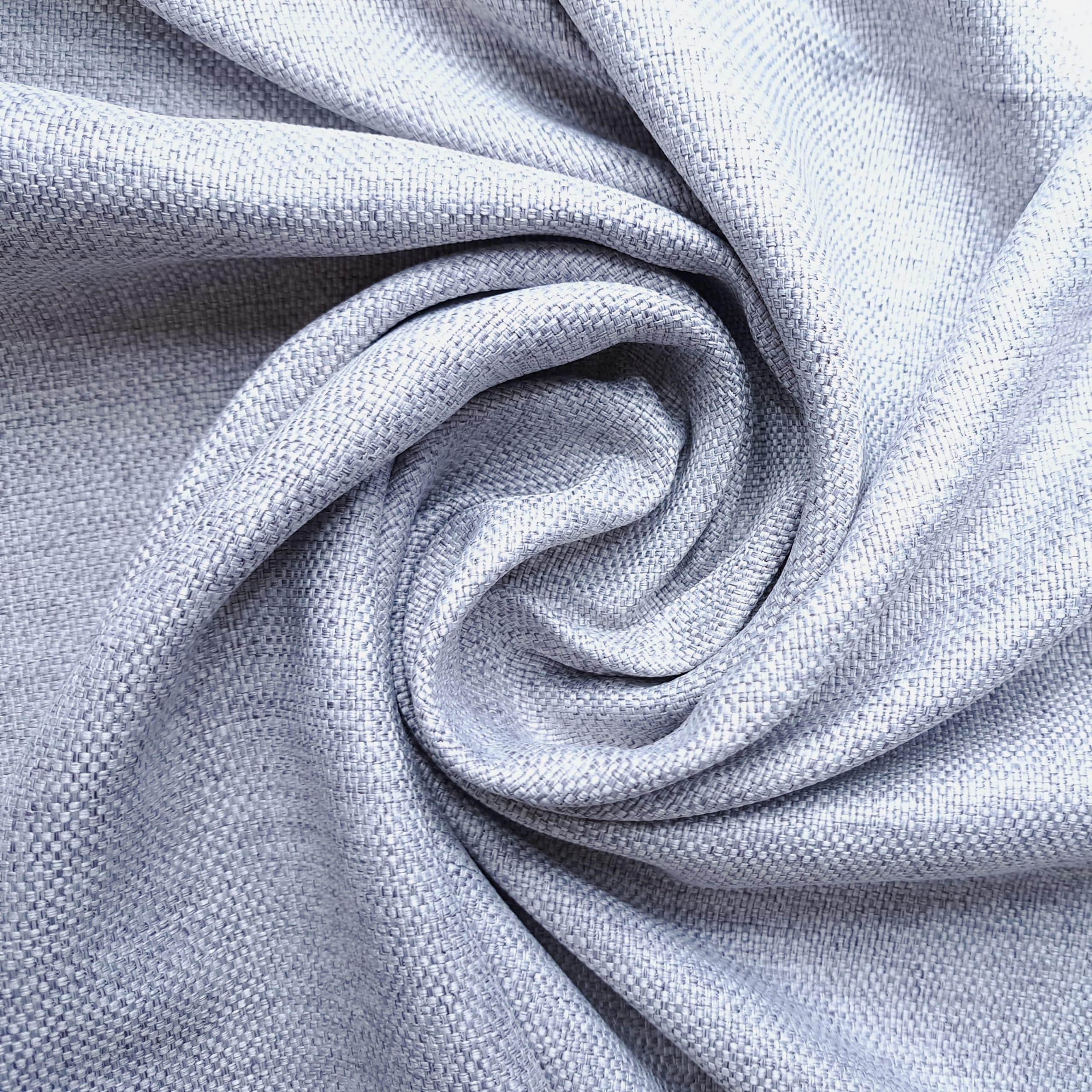 Zbliżenie na zwiniętą szarą tkaninę, faktura materiału.