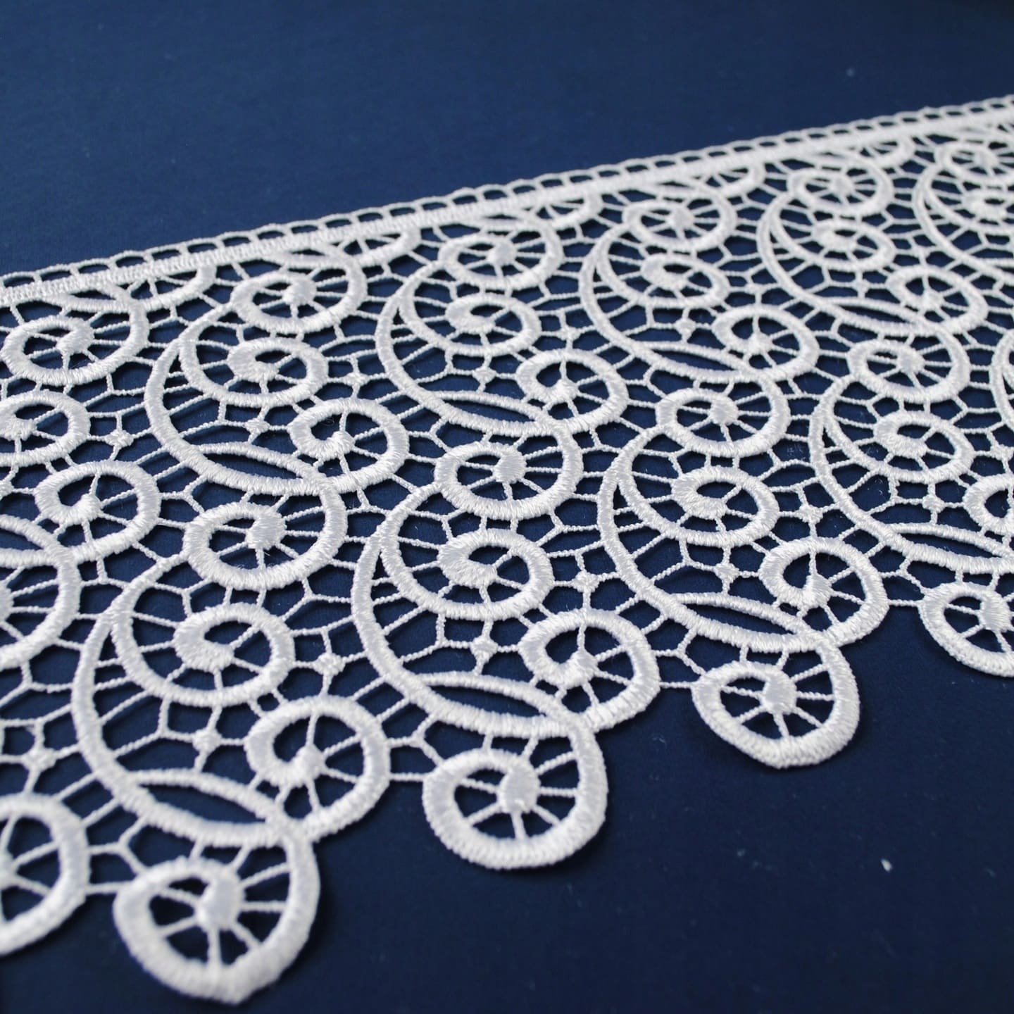 Biała koronka na niebieskim tle, skomplikowany wzór geometryczny, elegancki dodatek do dekoracji wnętrz.