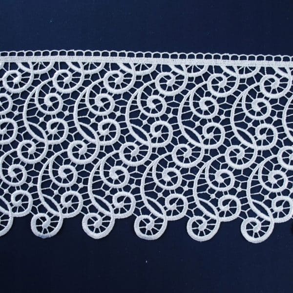 Koronkowy pas biegnący poziomo na ciemnym tle, ozdobiony białymi, skomplikowanymi wzorami.
