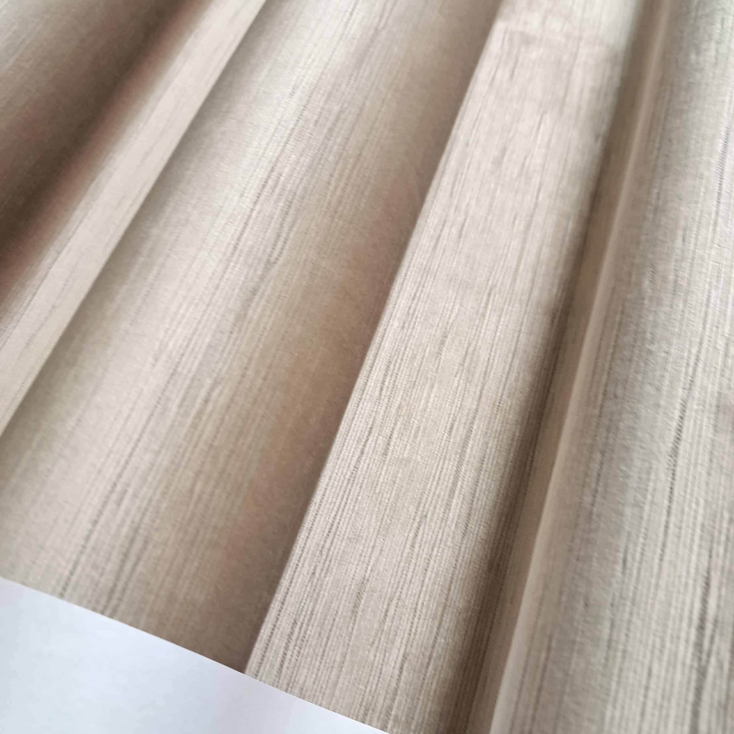 Beżowa tekstura tkaniny złożona w harmonijkę, wzór materiału o subtelnych liniach.