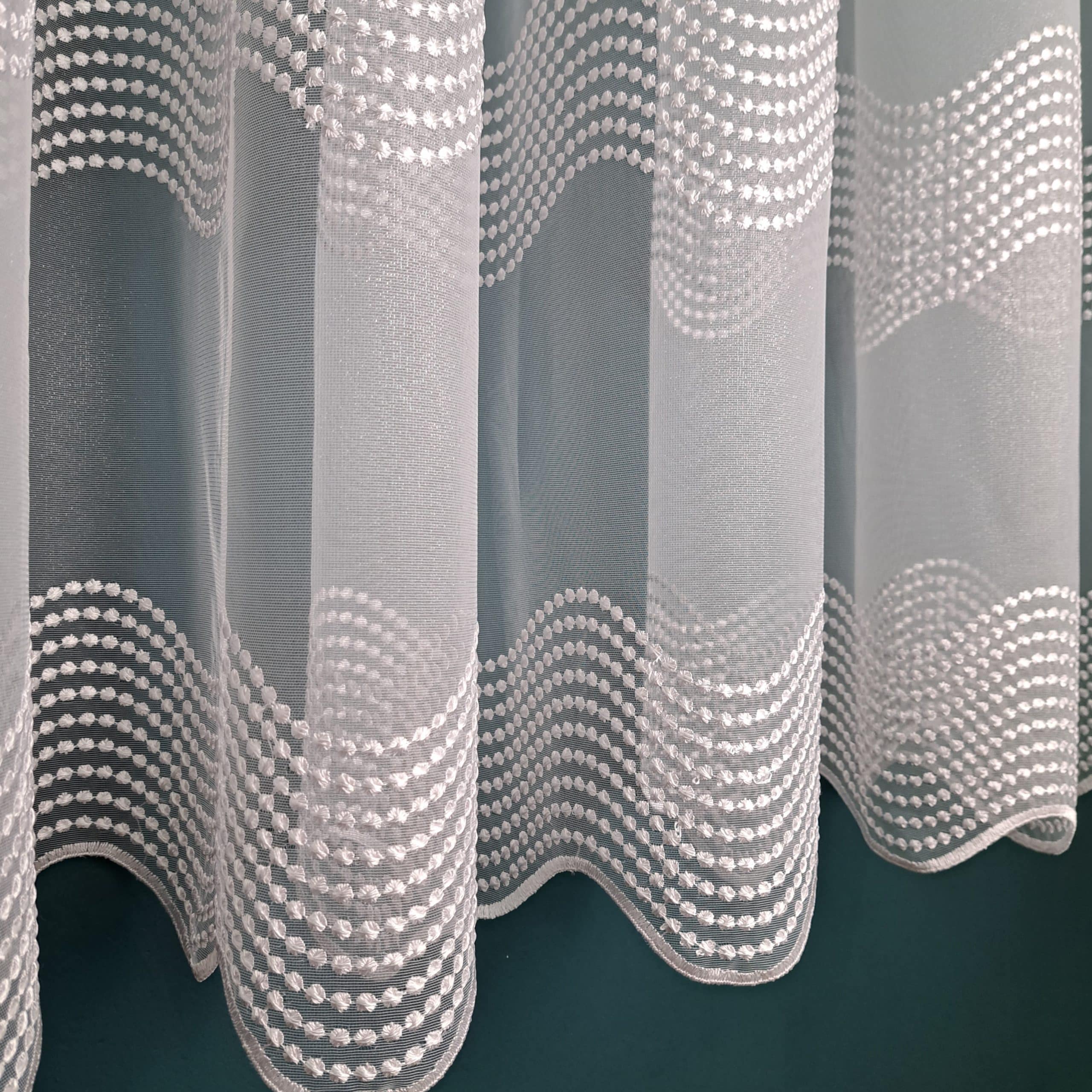 Biała zasłona z delikatnym wzorem fal i kropek, doskonała do nowoczesnego wystroju wnętrza.