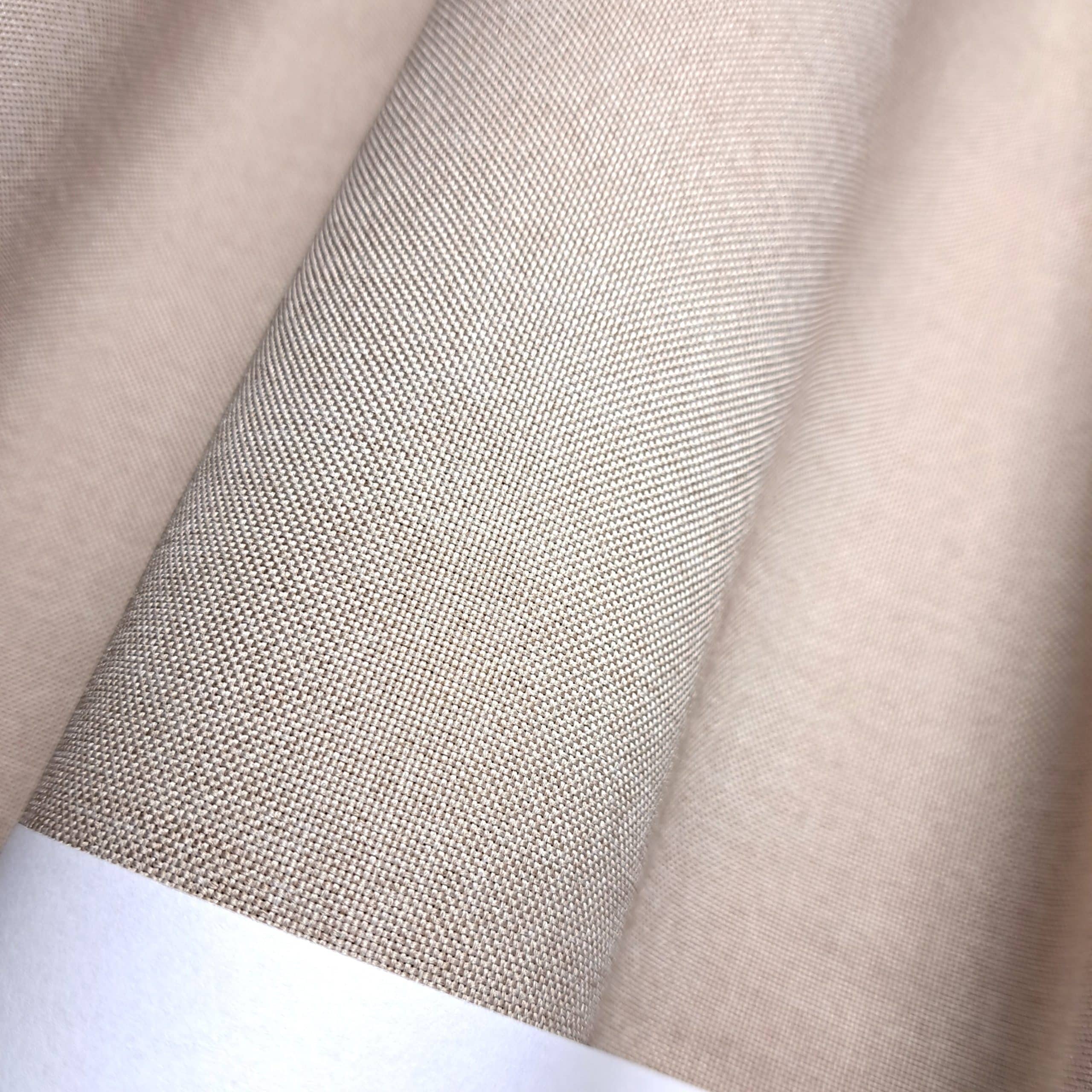 Zbliżenie na beżową, teksturowaną tkaninę o drobnym splocie.