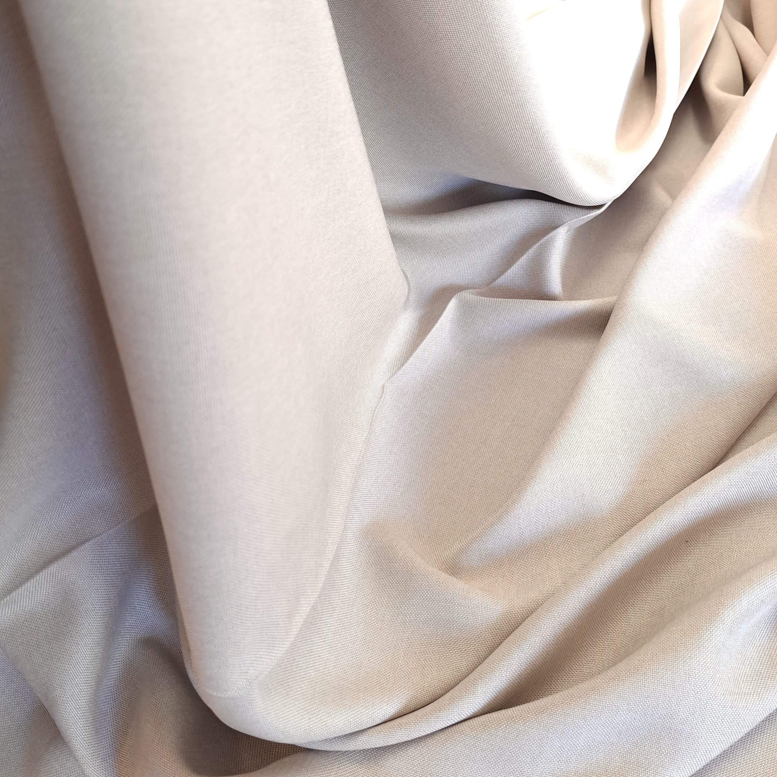 Elegancka beżowa tkanina gładko ułożona, idealna na dekoracje wnętrz lub modne ubrania.