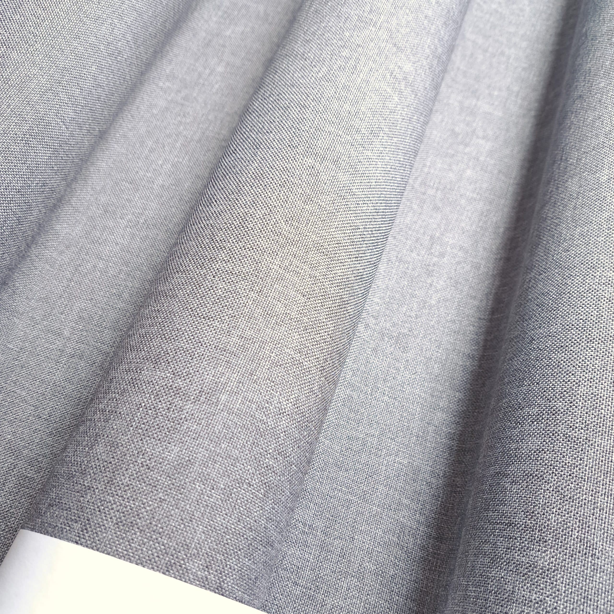 Gładki szary materiał zwinięty w fałdy, tekstura tkaniny ukazana z bliska.