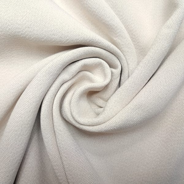 Beżowa tkanina ułożona w spiralę, tekstura materiału wyraźnie widoczna.