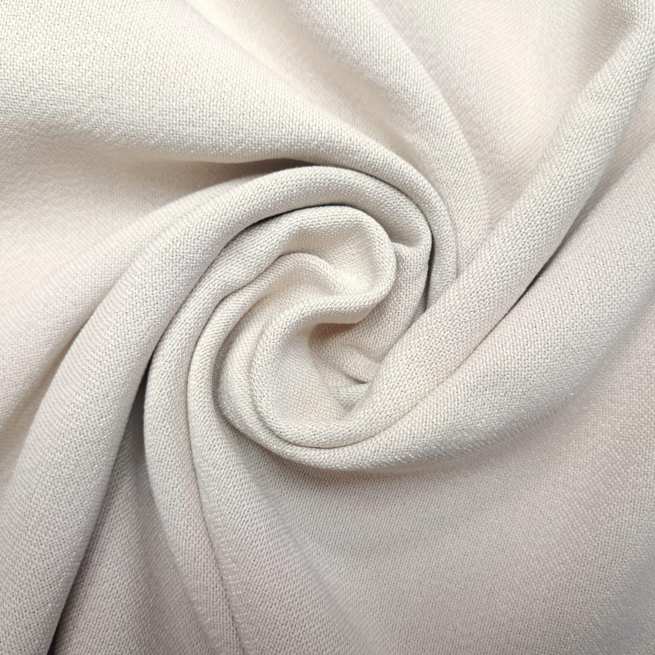 Beżowa tkanina ułożona w spiralę, tekstura materiału wyraźnie widoczna.