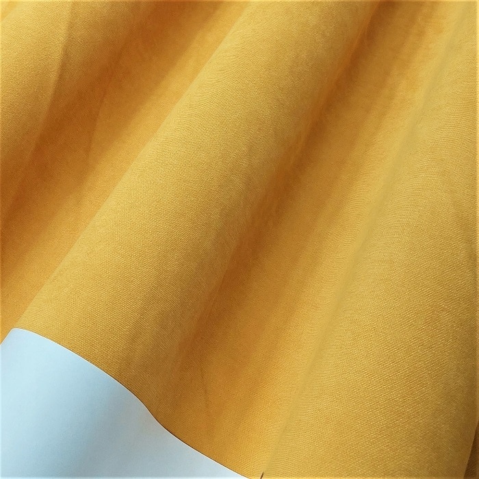 Żółta, miękka tkanina w falistym układzie, idealna na zasłony lub obrusy.